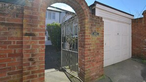 A brick archway leading to a garage with a metal gate and a sign reading "Rest Cottage". - 1 Bed in Southwold (oc-rest) (Southwold)