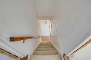 A staircase with a wooden handrail, carpeted steps, and a picture on the wall at the top. - 2 Bed in Swanage (oc-wy465) (Swanage)