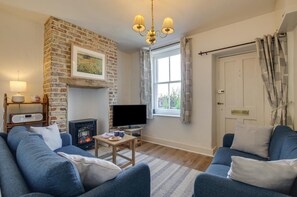 A living room with a brick fireplace, a television, two sofas, a coffee table, and a window with curtains. - 2 Bed in Swanage (oc-wy465) (Swanage)
