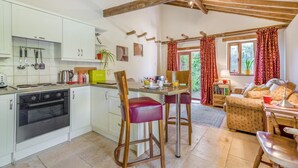 A modern kitchen with white cabinets, a built-in oven, and a dining area with a wooden table and chairs. - 1 Bed in Oulton (oc-a32857) (Lowestoft)
