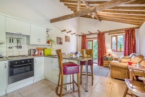 Une cuisine moderne avec des armoires blanches, un four encastré et un coin repas comprenant une table et des chaises en bois.