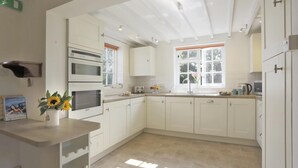 A modern kitchen with white cabinetry, a built-in oven, and a window providing natural light. - 3 Bed in Leiston (oc-wil) (East Bridge)