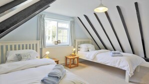 A bedroom with two beds, a window with curtains, a radiator, and a unique slatted ceiling design. - 3 Bed in Leiston (oc-wil) (East Bridge)