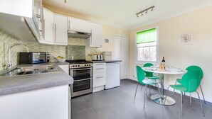 Cocina compacta con estufa, horno, microondas y lavaplatos.  Comedor con mesa y sillas.