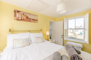 A bed with white linens and pillows, a bedside lamp, a window with shutters, and a painting on the wall. - 2 Bed in Weymouth (oc-wy492) (Weymouth)