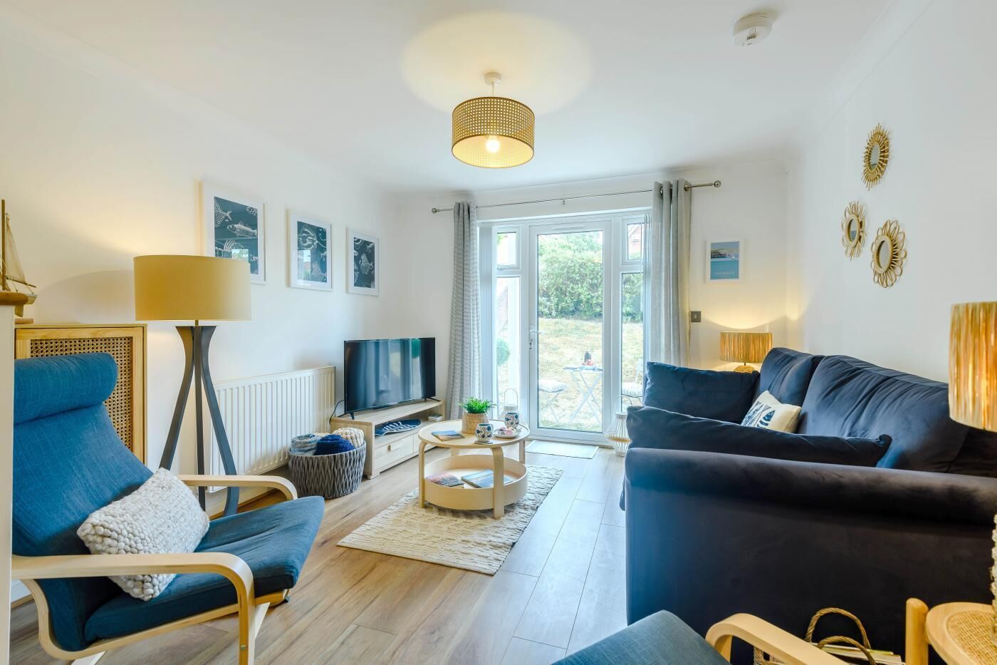Ein modernes Wohnzimmer mit Fernseher, zwei Sofas, einem Couchtisch und einem großen Fenster.