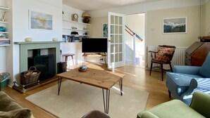 Uma sala de estar com lareira, televisão, mesa de centro e sofá.