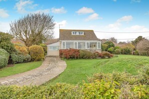 A house with a stone pathway leading to the entrance, surrounded by well-maintained hedges and a lawn. - 4 Bed in Worth Matravers (oc-wy115) (Worth Matravers)