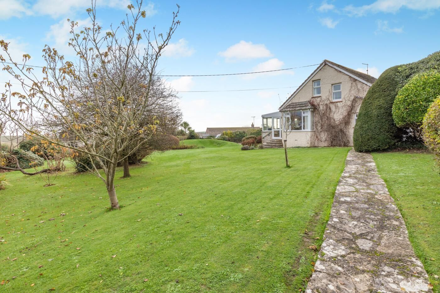 A house with a well-maintained lawn, a stone pathway, and a hedge.