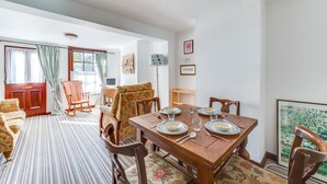 Un coin repas avec une table en bois dressée pour quatre personnes, entourée de chaises ornées de motifs floraux.