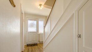Un pasillo con piso de madera, paredes blancas, una puerta con paneles de vidrio esmerilado y una lámpara.