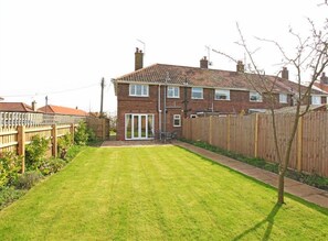 A residential property with a well-maintained lawn, a wooden fence, and a brick house with a tiled roof. - 2 Bed in Southwold (oc-deck) (Southwold)