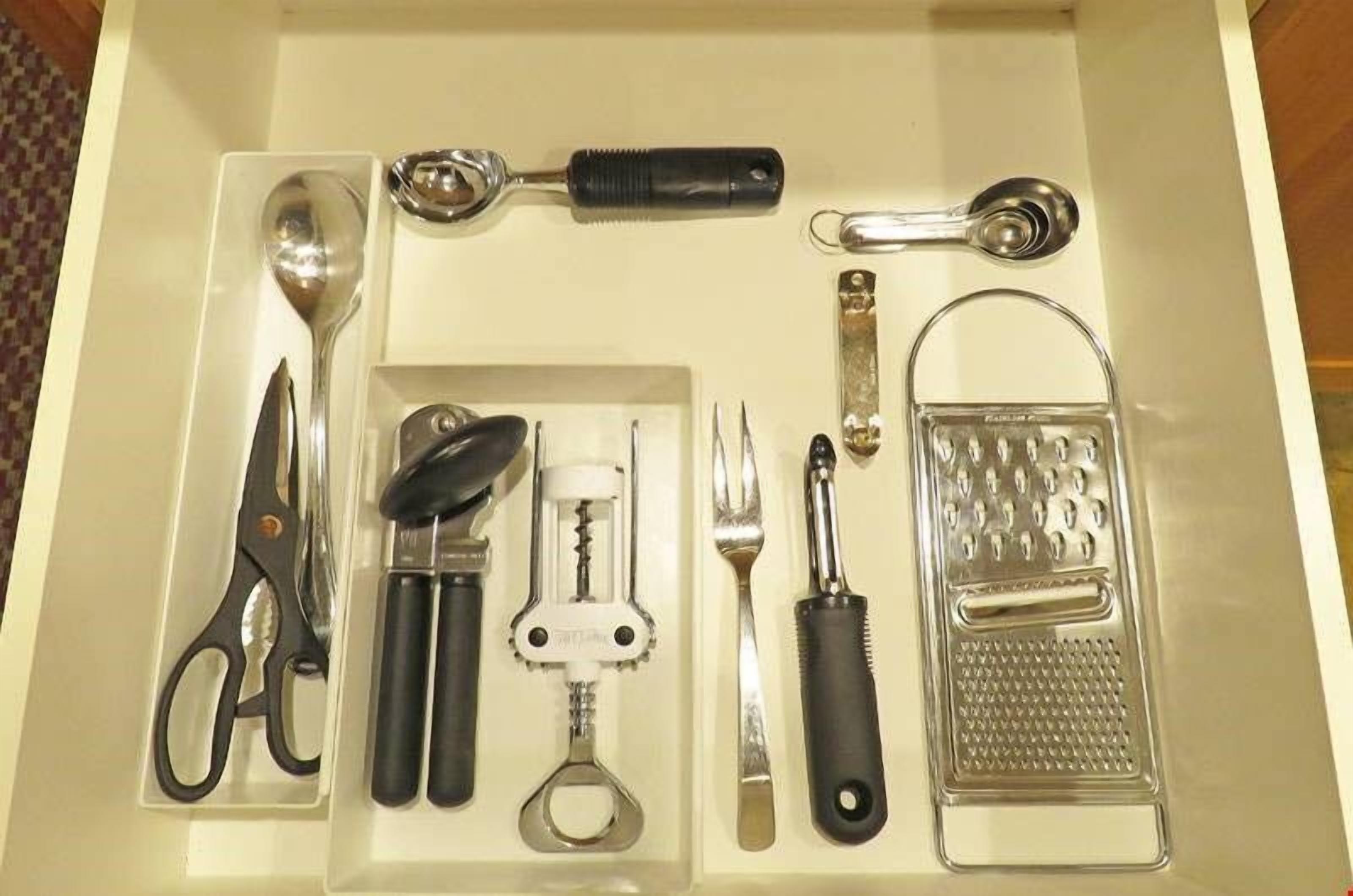 A drawer containing various kitchen utensils including scissors, a grater, and a corkscrew.