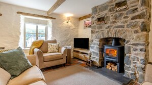 A cozy living room with a stone fireplace, a sofa, and a television. - 2 Bed in Cwmystwyth (oc-p32779) (Cwmystwyth)