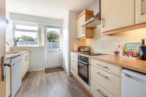 A compact kitchen with a built-in oven, a microwave, and a coffee machine. - 2 Bed in Reydon (oc-lowrd) (Reydon)
