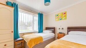 A bedroom with two beds, a wardrobe, a desk, and a window with curtains. - 2 Bed in Reydon (oc-lowrd) (Reydon)