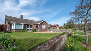A two-story brick house with a tiled roof, a front garden with flowers, and a clear sky. - 2 Bed in Reydon (oc-lowrd) (Reydon)