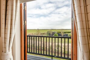 A balcony with a view of a green field and a clear sky. - 1 Bed in Woodbridge (oc-meb) (Sudbourne)