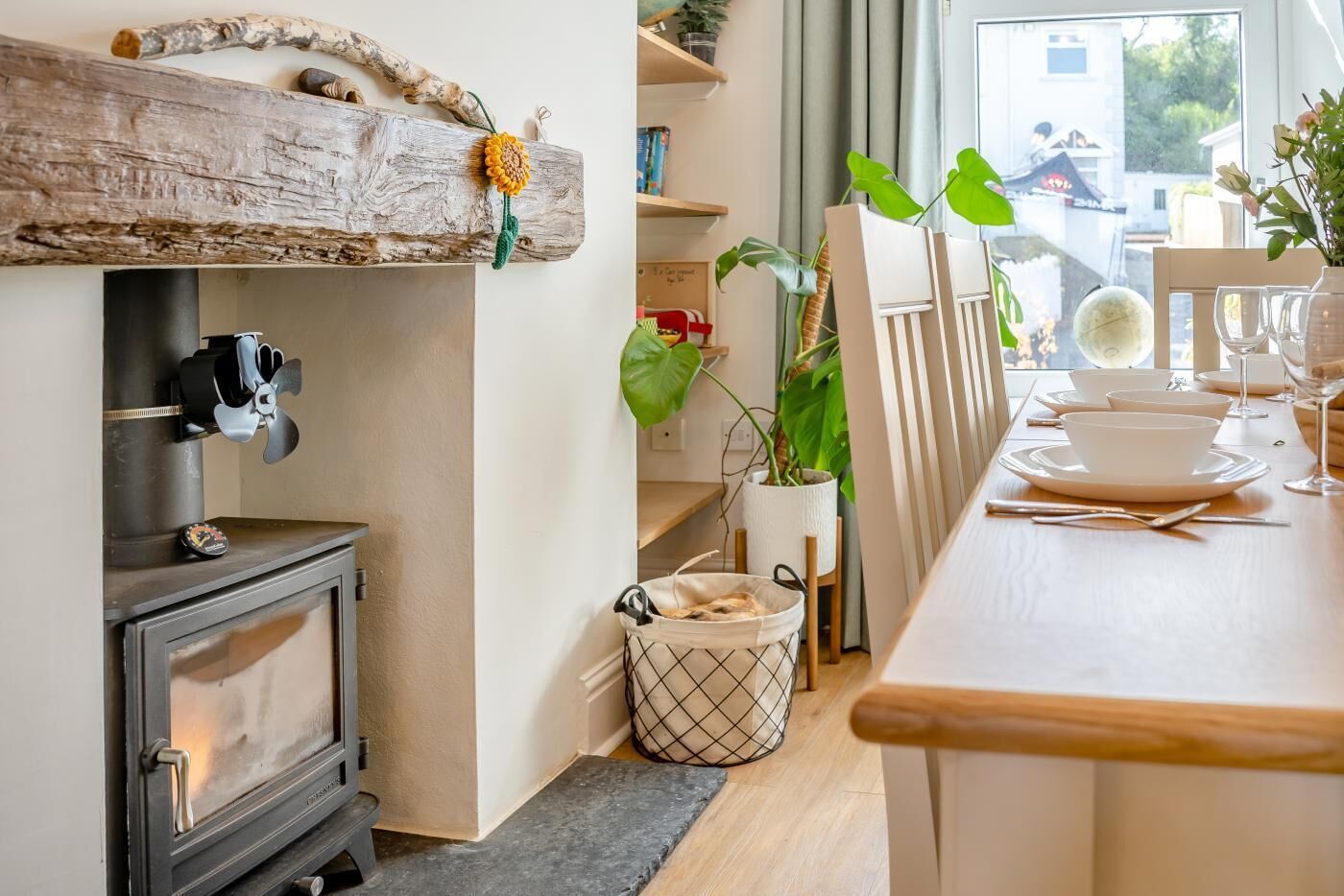 Et hyggeligt køkken med en brændeovn, et spiseområde med et bord dækket til to, og udsigt udad.