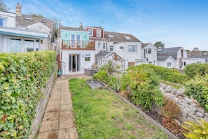 A residential property with a garden, a pathway, and a two-story house with a balcony.