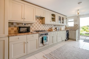 A kitchen with white cabinets, a microwave, a stove, and a dishwasher.