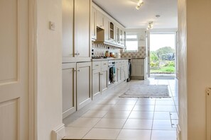 A kitchen with white cabinets, a stove, and a view of the outdoors.