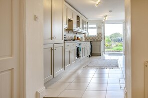 A kitchen with white cabinets, a stove, and a view of the outdoors.