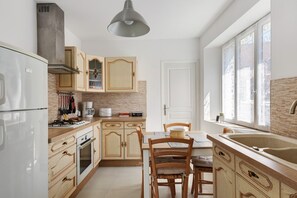 Eine Küche mit Holzausstattung, einem Gasherd, einem Kühlschrank und einem Fenster mit Verzierglas.