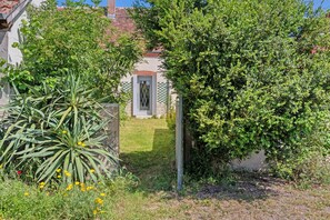 Ein Garten mit einem Weg, der zu einem Gebäude mit einer Tür und Fenstern führt.