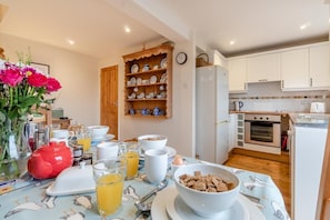 A breakfast setup with a table, breakfast items, and a kitchen area with appliances. - 3 Bed in Middleton (oc-htv) (Middleton Moor)
