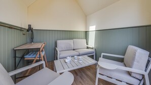 A cozy room with a loft bed, a small desk with a lamp, a sofa, and a coffee table.