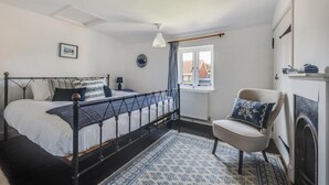 A bedroom with a bed, a chair, a window, and a fireplace.