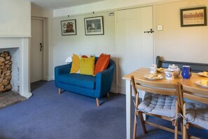 A cozy living room with a blue sofa, a dining table with chairs, and a fireplace. - 2 Bed in Wenhaston (oc-spdr) (Wenhaston)