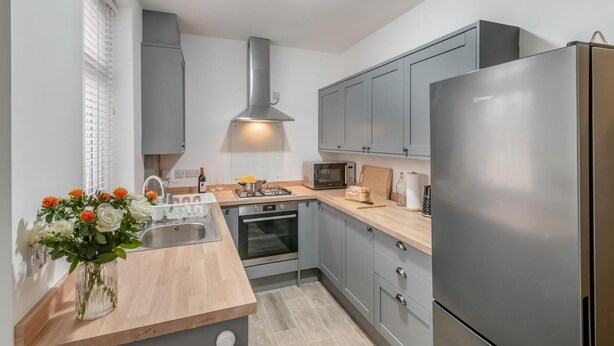 A modern kitchen with grey cabinets, stainless steel appliances, and a wooden countertop. - 3 Bed in Skipton (oc-g33088) (Skipton)