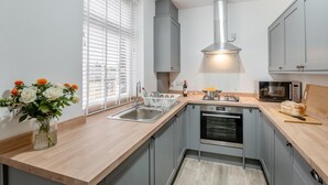 A modern kitchen with grey cabinets, a stainless steel sink, a built-in oven, and a microwave. - 3 Bed in Skipton (oc-g33088) (Skipton)