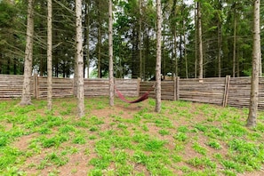 A fenced outdoor area with trees and a hammock.