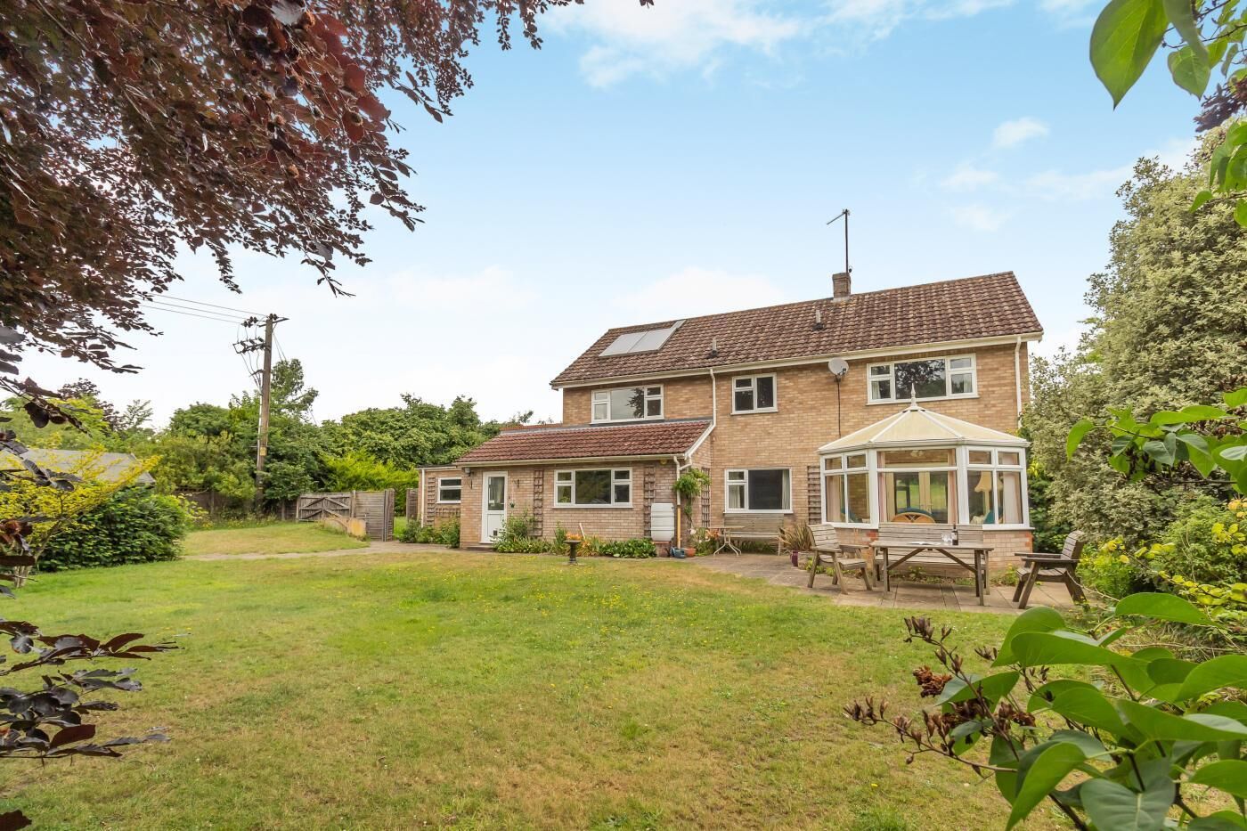 A two-story house with a conservatory, a garden, and a visible satellite dish.