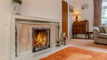 A living room with a fireplace, a sofa, a wooden dresser, and a bear figurine.