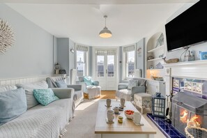 Ein Wohnzimmer mit Kamin, Sofas, einem Couchtisch und einem Fernseher.