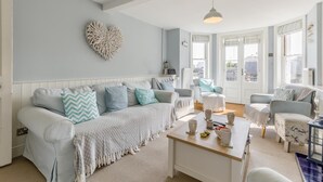 Uma sala de estar moderna com um sofá azul claro, uma mesa de centro e uma decoração de parede em formato de coração.