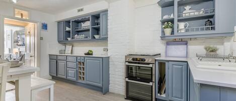 A modern kitchen with grey cabinetry, a built-in oven, and a white countertop.