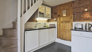 A kitchen with white cabinets, a wooden door, and a staircase. - 1 Bed in Woodbridge (oc-jsm) (Woodbridge)