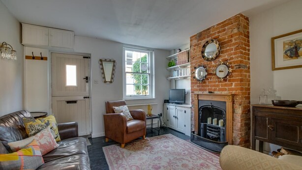 A cozy living room with a leather sofa, a brown armchair, a fireplace, and a bookshelf. - 1 Bed in Woodbridge (oc-jsm) (Woodbridge)