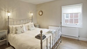 A bedroom with a metal-framed bed, a chandelier, a window with a view, and a radiator. - 1 Bed in Woodbridge (oc-jsm) (Woodbridge)