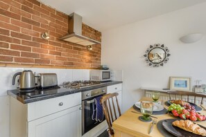 Een praktische keuken met een gasfornuis, waterkoker, broodrooster en magnetron.