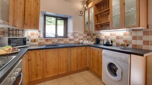 A kitchen with wooden cabinets, a microwave, a sink, a toaster, and a washing machine.