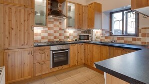 A kitchen with wooden cabinets, a gas stove, a microwave, and a window.