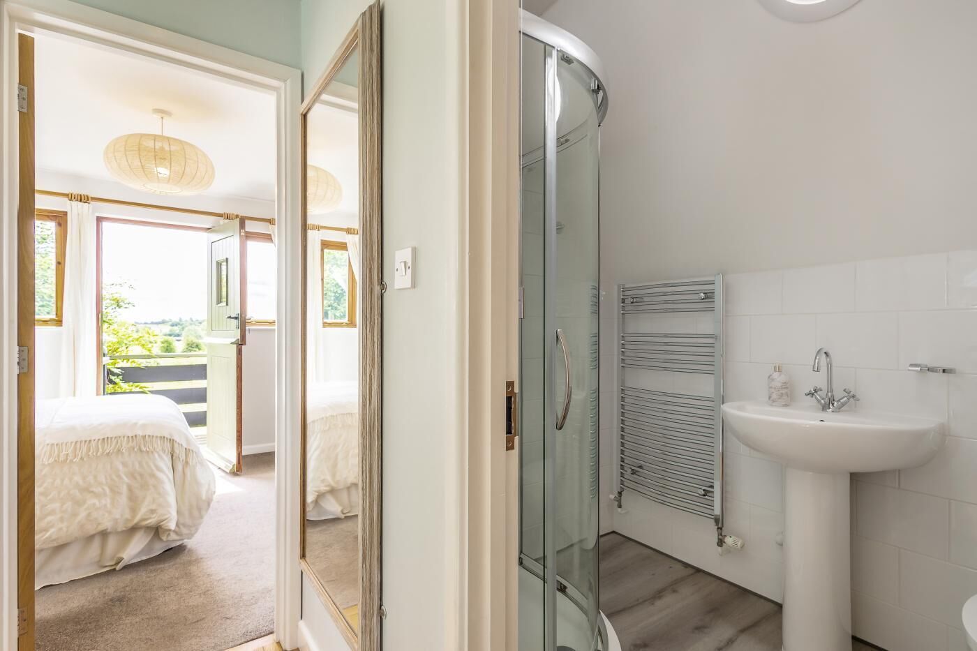 Una camera da letto con un letto, un bagno con lavandino e doccia, e una porta vetrata che dà su un balcone.