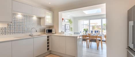 A modern kitchen with a central island, a dining area with natural light, and a view to the outdoors.