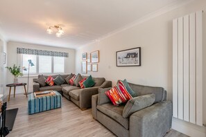 Ein modernes Wohnzimmer mit zwei Sofas, einem Couchtisch und einem gemusterten Teppich.